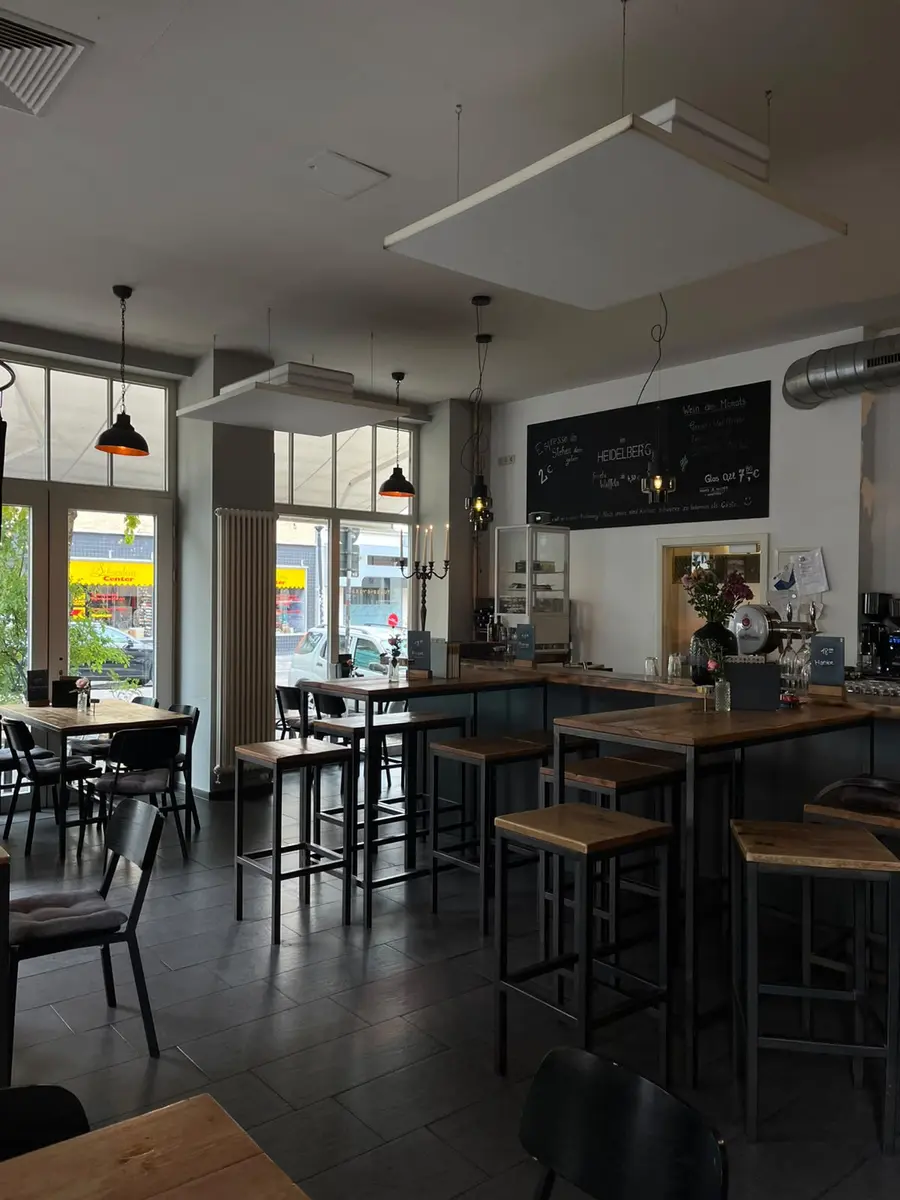 Gastraum des Café Heidelberg mit Hochtischen, Pendelleuchten und der großen Kreidetafel