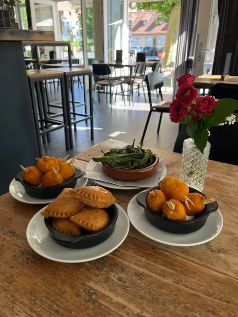 Tapas auf dem Holztisch: Empanadas, Kroketten und gebratene Pimientos